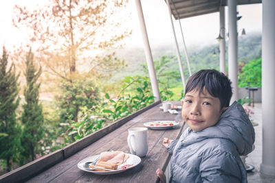 Portrait of boy sitting by window