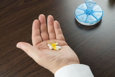 Close-up of human hand holding medicines on table