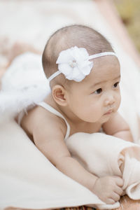 Cute baby girl wearing costume wing while lying on blanket