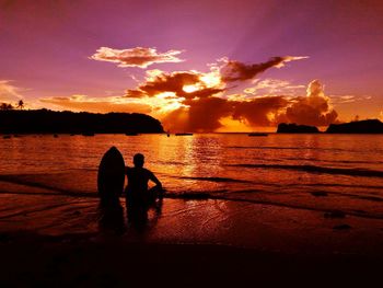 Silhouette people on beach against sky during sunset