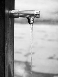 Close-up of water drop on metal against sky