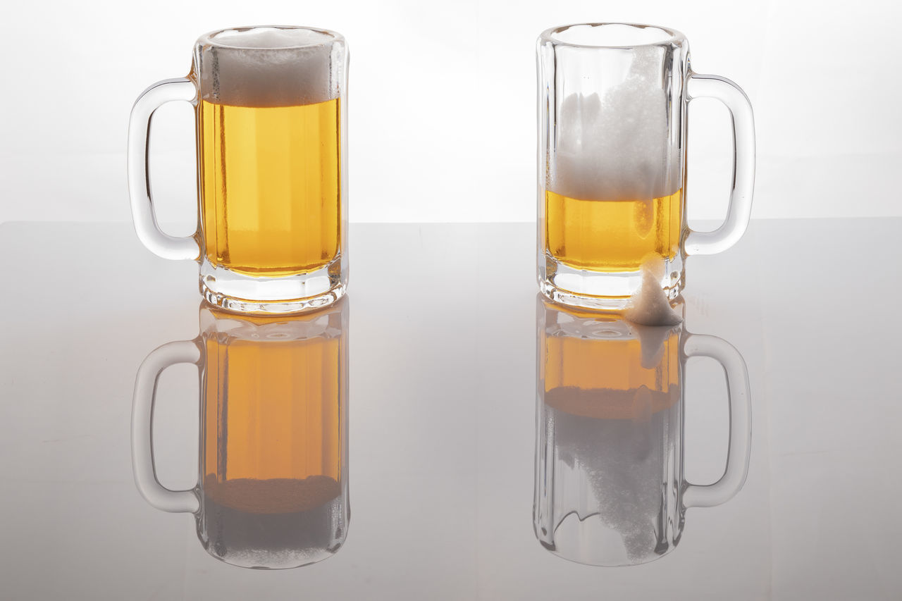 CLOSE-UP OF BEER GLASS ON TABLE AGAINST BACKGROUND