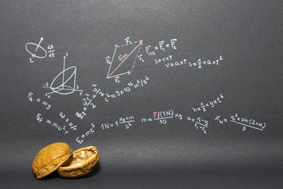 Close-up of walnut against formulas on blackboard