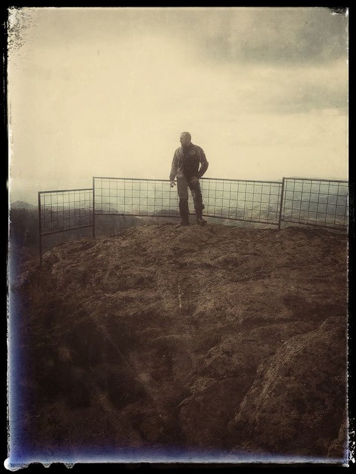 MAN STANDING BY FENCE