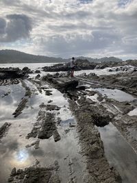 Man standing on rock against sky