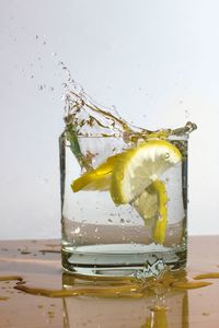 Glass of water splashing against gray background