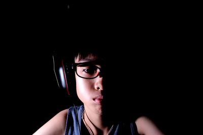 Close-up of boy wearing eyeglasses against black background