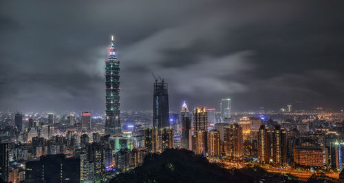 Illuminated modern buildings against sky at night