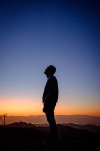 Silhouette of man on mountain against sky at sunset