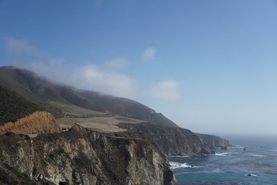 Scenic view of sea and mountains against blue sky