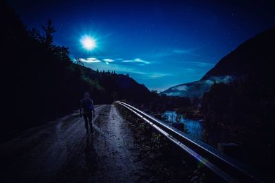 Man on railroad track against sky at night