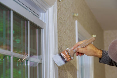 Midsection of man holding hands on window