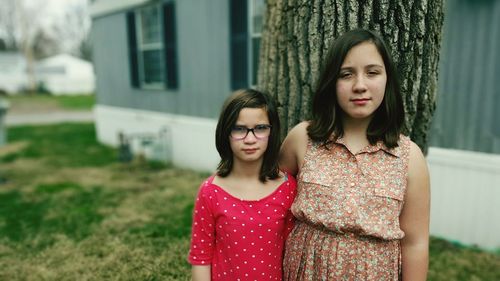 Portrait of sisters standing in yard