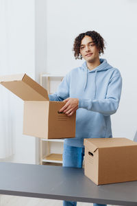 Portrait of young woman holding box against white background