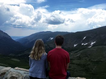 Rear view of people looking at mountains against sky