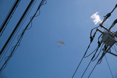 Low angle view of airplane flying against clear blue sky