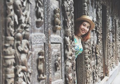 Portrait of smiling young woman standing at doorway in temple