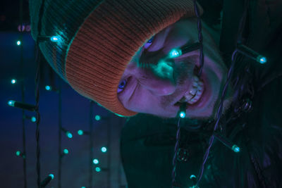 Portrait of man biting illuminated lighting equipment