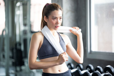 Young woman holding towel while looking away in gym