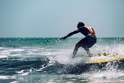 Man surfing on sea against clear sky