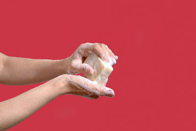 Woman washing hands with soap on a red background