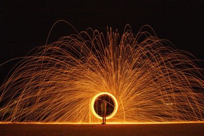Full length of man making wire wool against sky at night