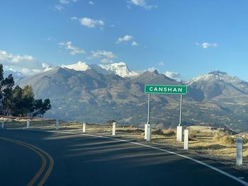 Road sign by mountains against sky