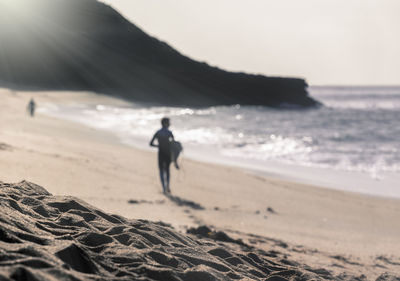 Silhouette man carrying surfboard at beach