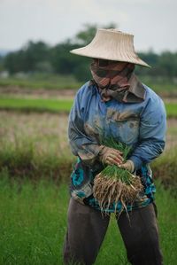 Midsection of person wearing hat standing on field
