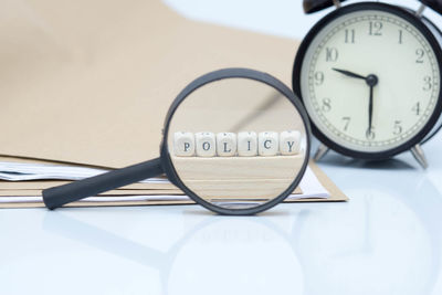 Policy text made of toy blocks with files and magnifying glass on white background