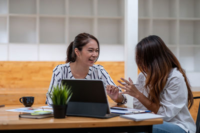 Young woman using phone while sitting on table