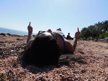 Rear view of person relaxing on land against sky