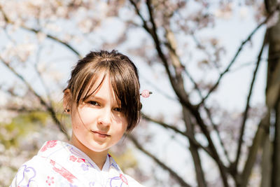 Close-up portrait of teenage girl standing against bare trees