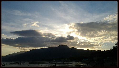 Scenic view of mountains against cloudy sky at sunset