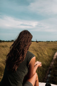 Woman sitting against field