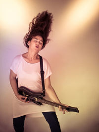 Woman playing guitar against colored background