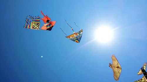 Low angle view of multi colored kites flying in sky