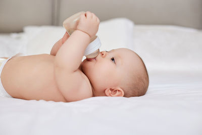 Midsection of shirtless baby girl lying on bed at home