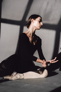 Young woman looking away while sitting on floor