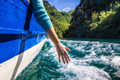 Low section of man on boat in sea against sky