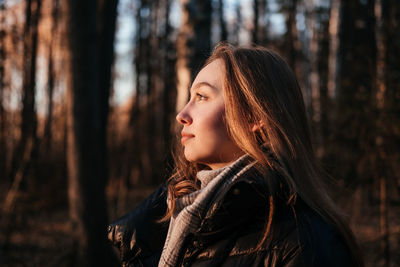 Side view of young woman standing in forest