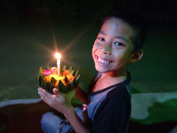 Portrait of smiling boy holding burning outdoors