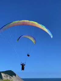 Low angle view of person paragliding against clear blue sky