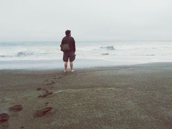 Full length rear view of a man standing on beach