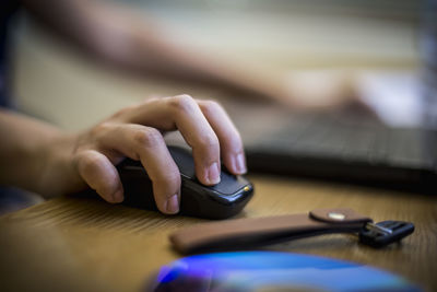 Cropped hand of person holding computer mouse by key on desk