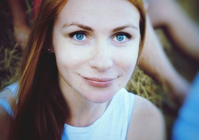 Close-up portrait of smiling woman sitting on field