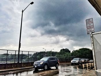 Cars on road against cloudy sky