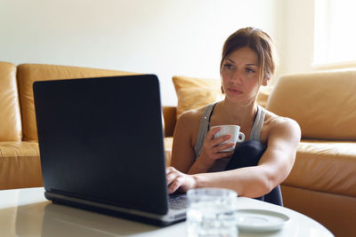 Young woman using mobile phone while sitting on sofa