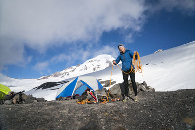 A female mountaineer winds her rope in front of her tent at base camp, mt. baker