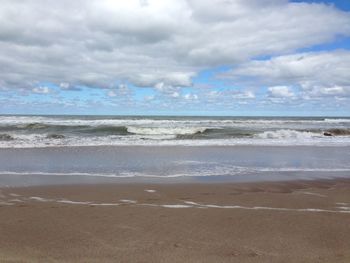 Scenic view of beach against cloudy sky